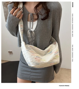 Detail of white dumpling bag with colorful wavy embroidery and quilted fabric texture