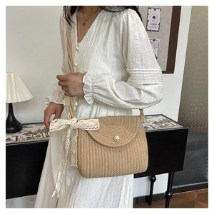 Detail of beige woven crossbody bag featuring a large pearl button and lace ribbon bow