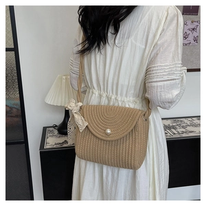 Detail van de handgeweven strooien crossbodytas met parelgesp en witte kanten strik decor
