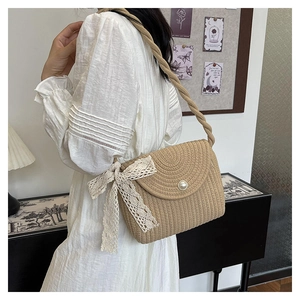 Detail of straw bucket bag featuring pearl buckle, lace bow, and rope shoulder strap