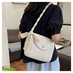 Straw shoulder bag with pearl button, lace bow and rope strap shown on female model