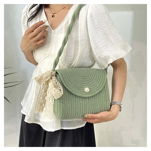 Detail of green woven shoulder bag featuring a pearl button and lace bow accent