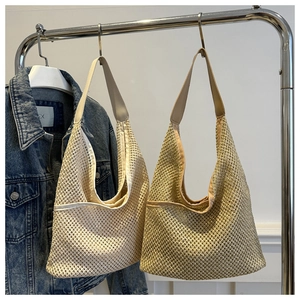 Detail of handmade woven straw shoulder bags in beige and light brown with PU straps
