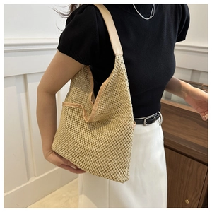 Detail of hollow-out straw texture and leather trim on this stylish woven shoulder tote bag
