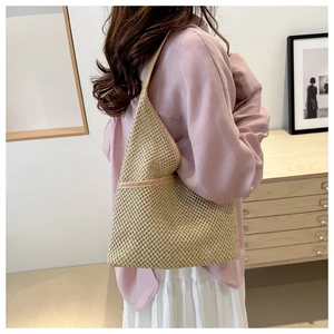 Detail of a minimalist straw tote bag with cream leather trim shown on shoulder
