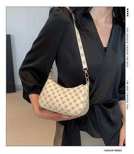 Close-up of cream shoulder bag with floral pattern and golden metal ring hardware