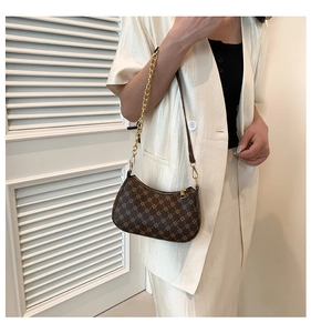 Detail of vintage crescent shoulder bag featuring retro pattern and gold chain strap