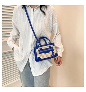 Detail of woven straw crossbody bag with blue leather trim and tassel on a model