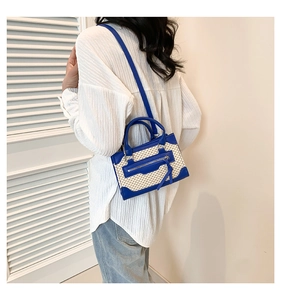 Detail view of woven straw crossbody bag in blue and beige with long decorative tassels