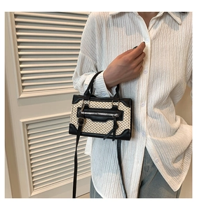 Detail of vintage square bag showing woven texture and black leather handles
