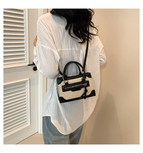 Sac à main en paille tressée avec bordure en cuir noir et détails de franges sur modèle