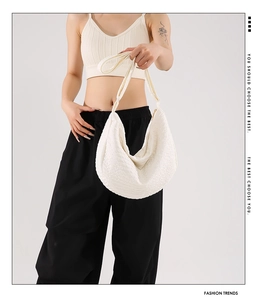 Close-up of white hobo bag with textured fabric and wide shoulder strap on model