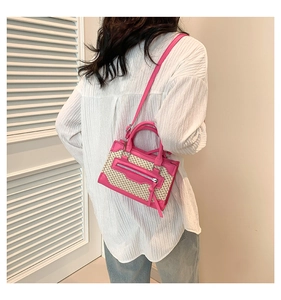 Détail du sac bandoulière en cuir rose et paille tressée porté par un mannequin