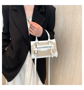 Detailed view of woven straw handbag with white leather trim and zipper accents