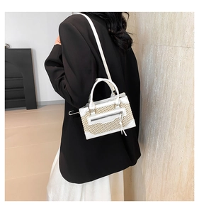 Détail du sac bandoulière tressé avec bordure en cuir blanc et gland long sur un modèle