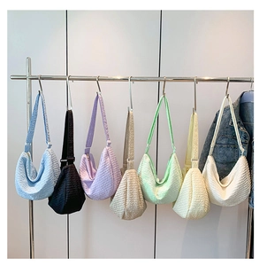 Detail showing seven vibrant colors of pleated dumpling bags hanging on a rack
