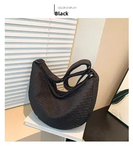 Detail of black dumpling bag featuring bubble textured fabric and adjustable strap
