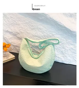 Detail of light green hobo bag featuring unique crinkled texture on a wooden surface