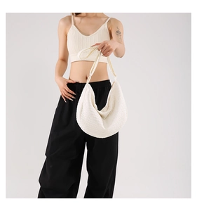 Detailed view of a white crescent shoulder bag with a unique quilted woven texture design