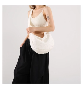 Detailed side view of a white pleated crescent bag featuring textured fabric and wide strap
