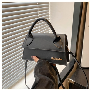 Detail of black textured leather handbag featuring golden logo and metallic hardware