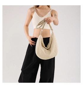 Close-up of beige waffle texture dumpling bag with wide shoulder strap on model
