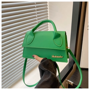 Detail of bright green leather handbag featuring gold logo and curved top handle