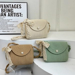 Three minimalist straw woven crossbody bags with pearl buttons and lace bows on display
