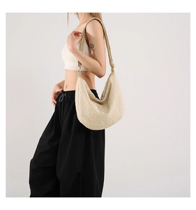 Detail of beige crescent bag featuring pleated fabric texture and adjustable strap
