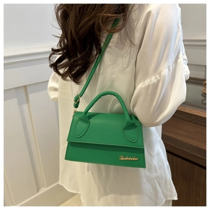 Detail of green leather handbag featuring a gold letter logo and smooth finish texture