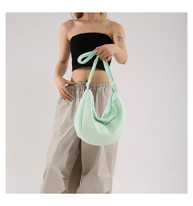 Detail of mint green dumpling tote bag featuring unique pleated fabric and adjustable strap