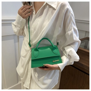 Modella che indossa una borsa a tracolla verde brillante con logo dorato e patta a busta