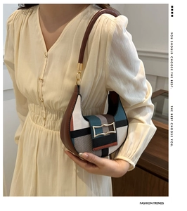 Detail of canvas leather patchwork crescent bag with a gold geometric lock and strap