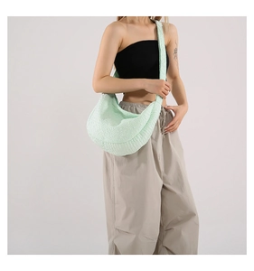 Detail of mint green half-moon crossbody bag featuring a textured woven fabric finish