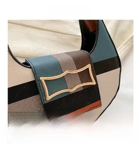 Detail shot of checkered crescent saddle bag featuring gold metal buckle and woven texture