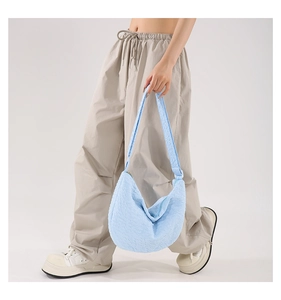 Close-up of light blue pleated hobo bag with textured fabric and wide shoulder strap