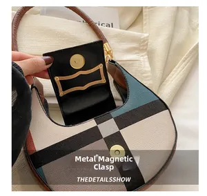Detail of magnetic snap clasp and gold hardware on the checkered crescent saddle bag