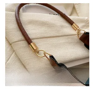 Detailed macro view of the golden metal rings connecting the brown leather handle to the canvas bag