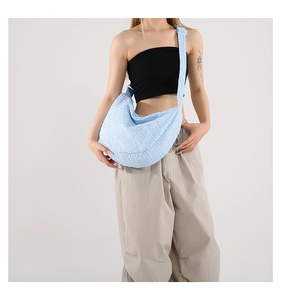 Detail of light blue popcorn fabric crossbody bag with textured popcorn texture and strap