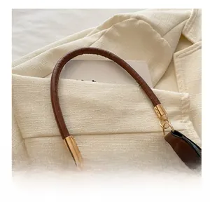 Detail of brown litchi pattern leather handle with gold metal buckle on a shoulder bag