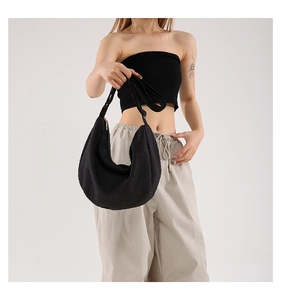 Close-up of black crescent bag with textured quilted fabric and adjustable shoulder strap