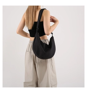 Modern black crescent shoulder bag with quilted texture and adjustable wide strap