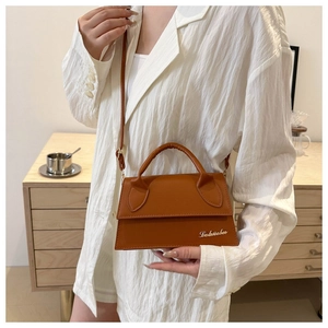 Detail of caramel mini crossbody bag with gold logo and wide handle on model