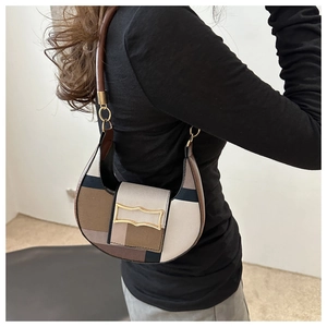 Detail of colorblock saddle bag featuring canvas patchwork and a gold metal buckle