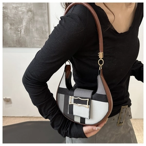 Detail of a color-block patchwork crescent hobo bag with a gold buckle worn on shoulder