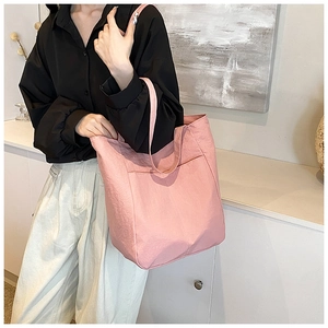 Detail of pink nylon tote bag with front pocket showing fabric texture and shoulder strap