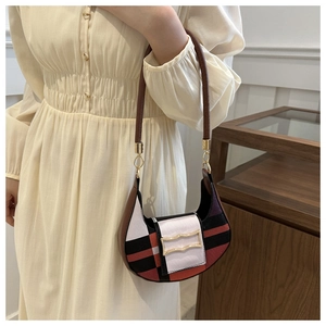 Detail of color-block hobo bag with gold hardware worn by model in minimalist setting