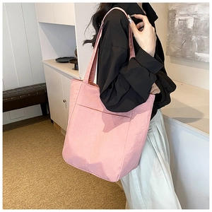 Detail of pink nylon tote bag showing textured waterproof fabric and front pocket