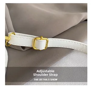 Detail showing adjustable white leather shoulder strap with gold-tone buckle for handbag