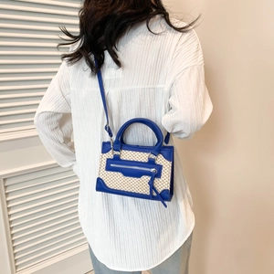 Sac bandoulière tissé bleu et beige avec poignée cylindre et bandoulière sur modèle